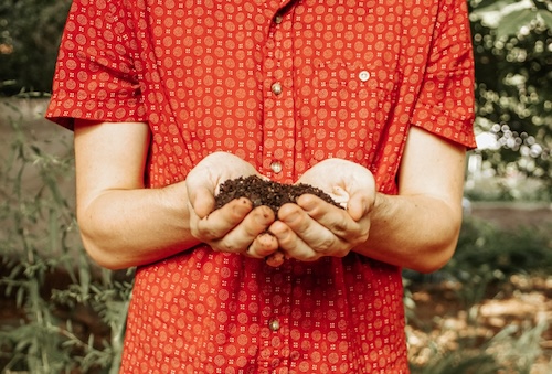 a pair of hands holding a small pile of dirt
